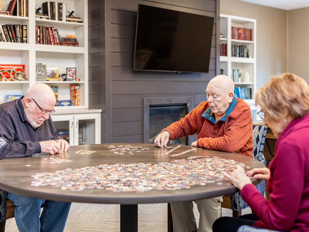 Group of senior citizens collaborating on a jigsaw puzzle in our community.
