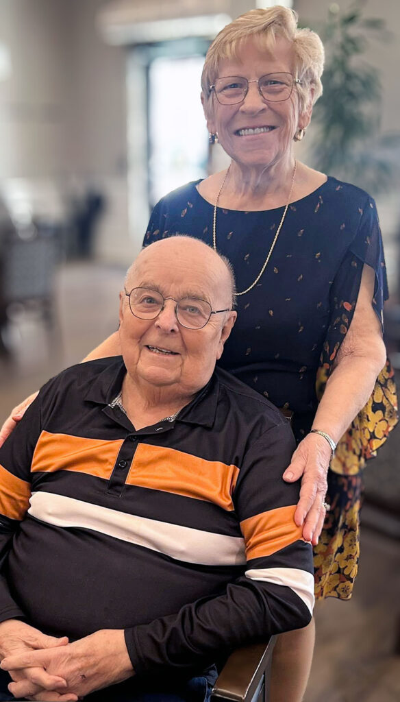 A senior man and woman smile joyfully at Vitalia North Olmsted.