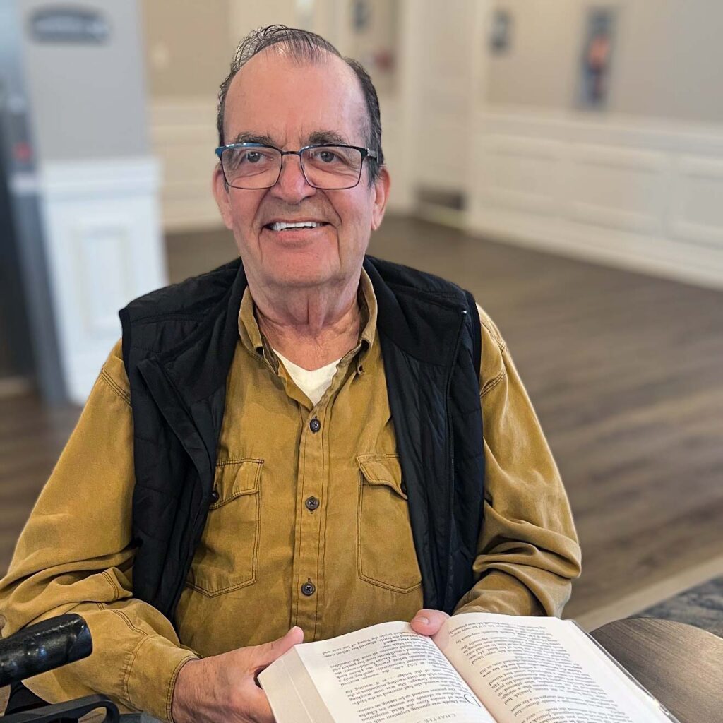 A senior man smiles while reading at Vitalia North Olmsted.