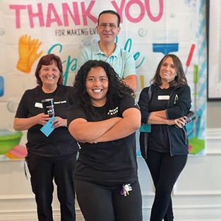 Four team members smile, posing playfully, in front of an Employee Appreciation backdrop at Vitalia North Olmsted.