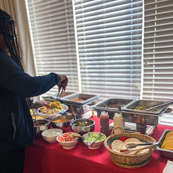 A team member fills up a plate from a large spread of various foods during a team meal event.