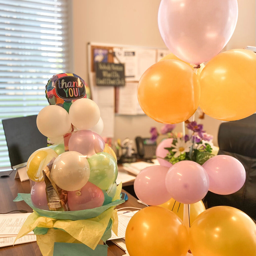 Two large, colorful bunches of balloons decorate gift baskets given in gratitude during Employee Appreciation.