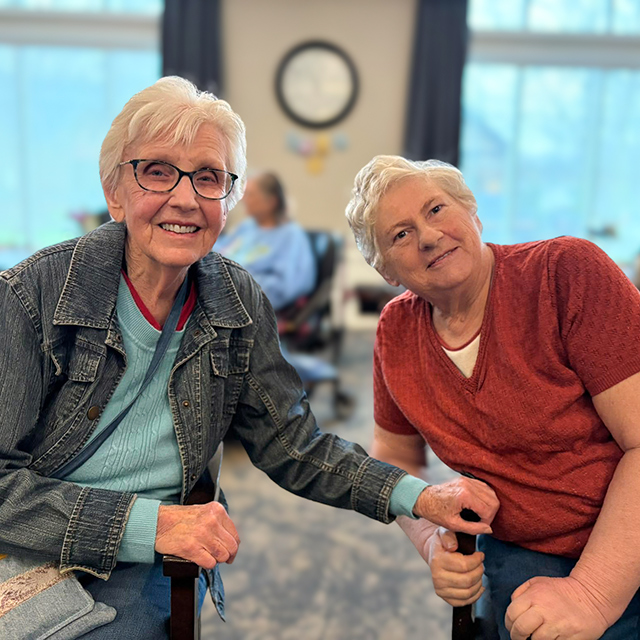 Two senior women smile during a relaxed moment of connection at Vitalia North Olmsted.